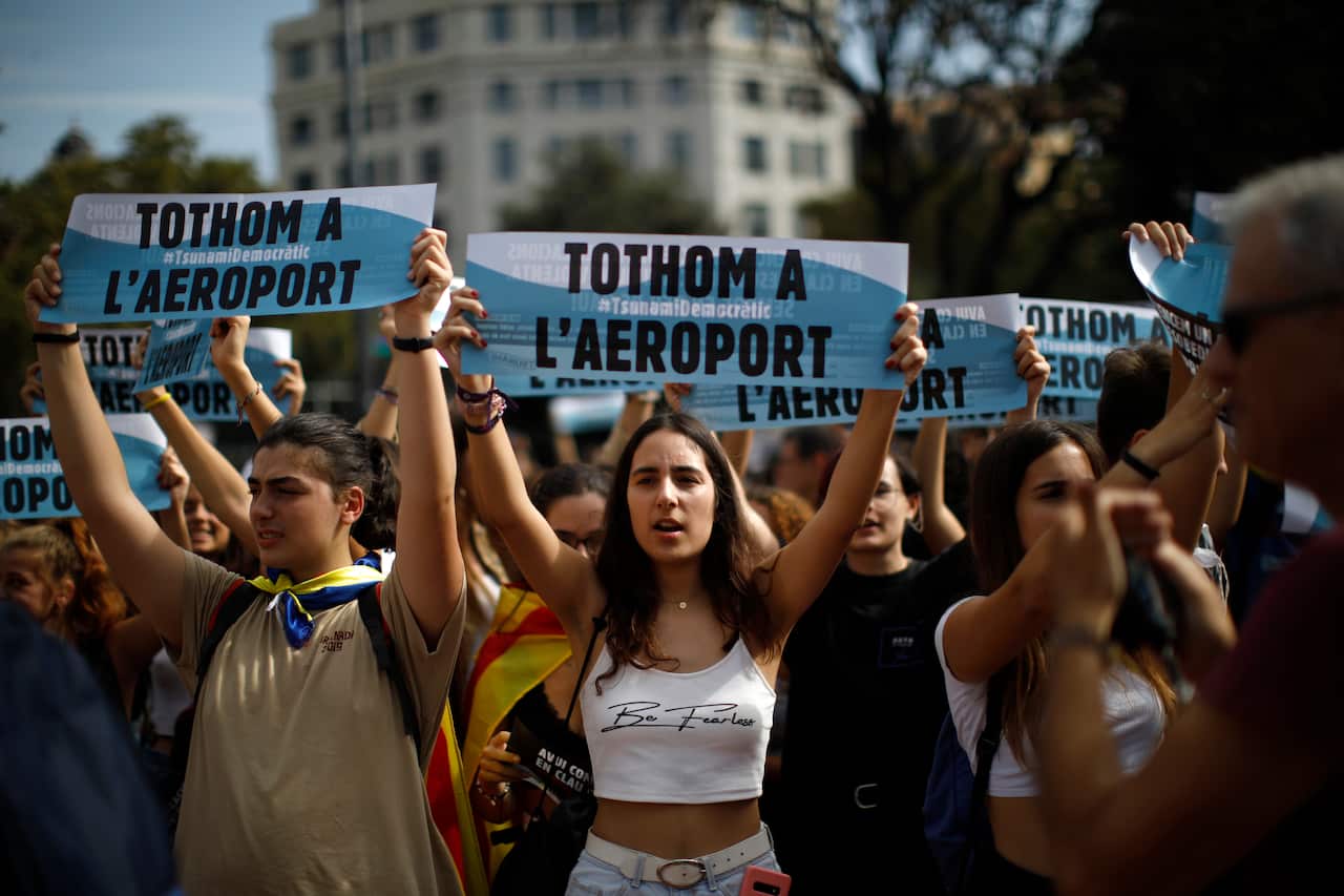 Young people hold up signs in Catalan reading "Everybody to the airport" during protests in Barcelona, Spain.
