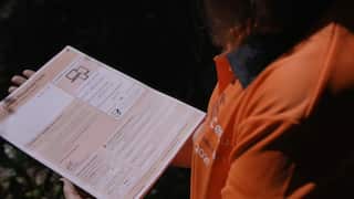 A man wearing an orange shirt holds the orange 2021 Census form.