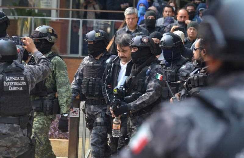 Mexican security forces surround the accused drug lord after his re-capture. 