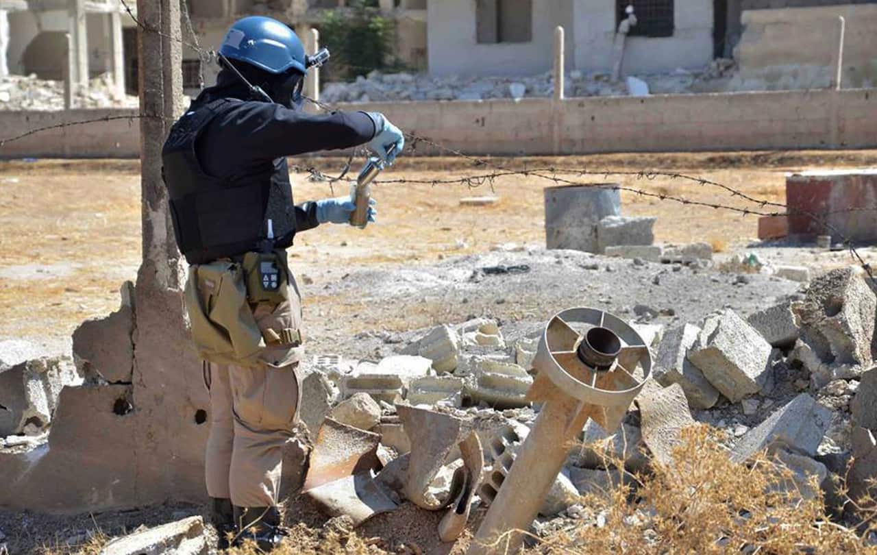 A member of UN investigation team taking samples of sands near a part of a missile is likely to be one of the chemical rockets in Damascus in 2013 (AAP)