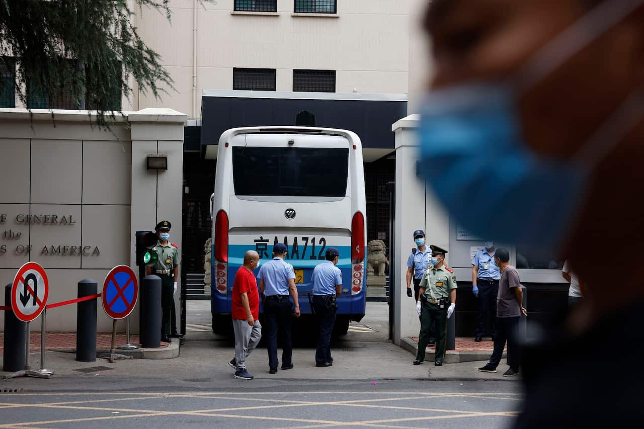 Chinese paramilitary policemen guard the gates as it opens to let a bus enter the United States Consulate in Chengdu.