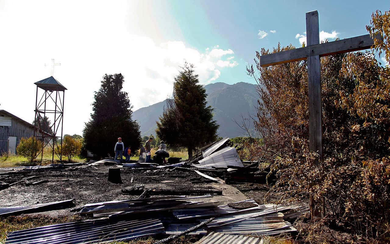 People search through the charred remains of the Santa Juana Catholic chapel in the Alta Can Can community in Cunco, Chile, Tuesday, Jan. 16, 2018. 
