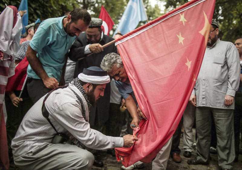 Uighurs living in Turkey prepare to set fire to a  Chinese flag outside the Chinese consulate in Istanbul.