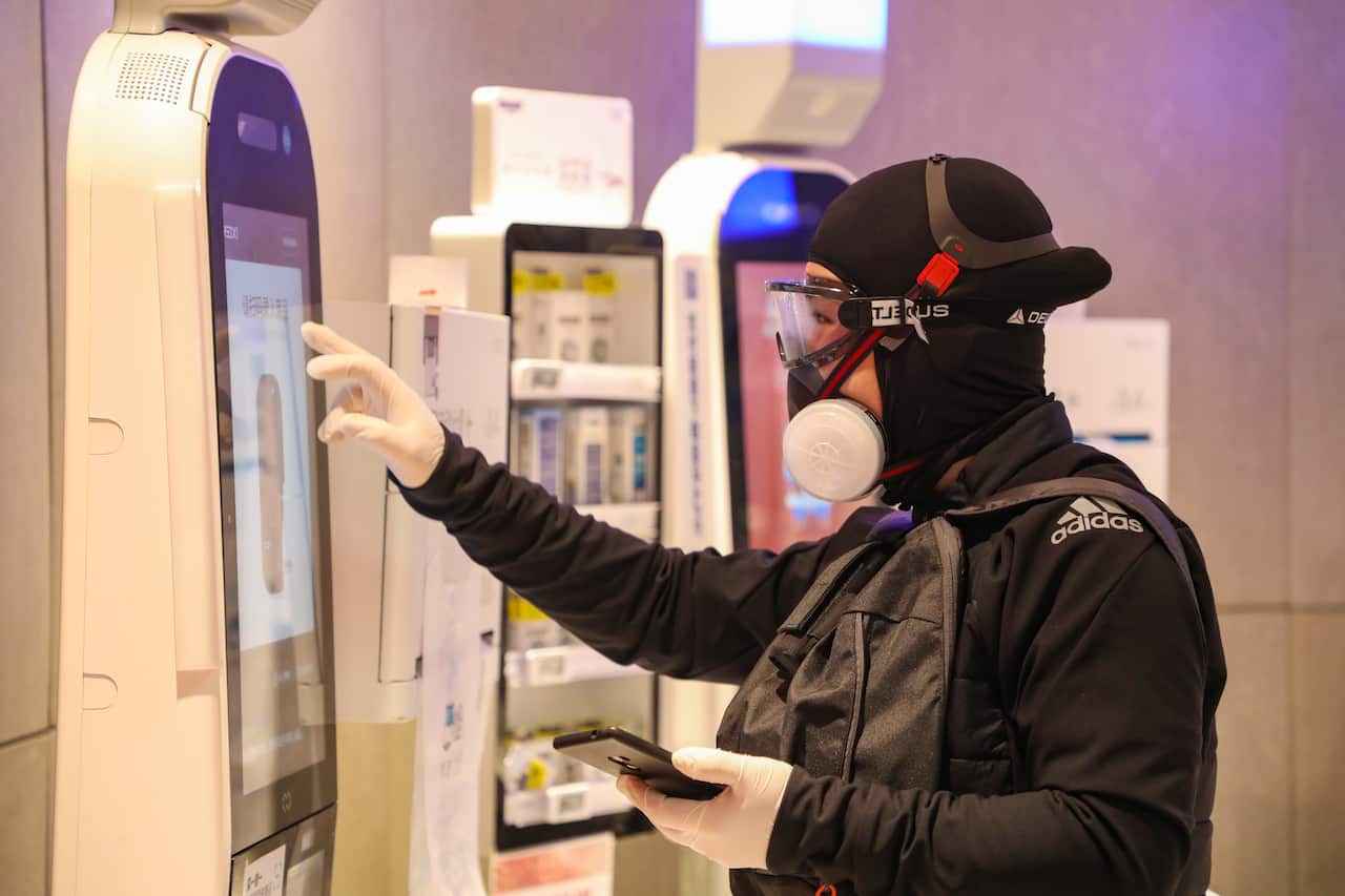 A fully-protected man uses the self-help machine of a supermarket in Wuhan.