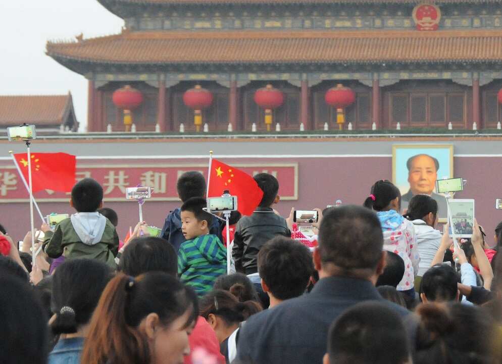 People wave flags in front of a portrait of former Chinese leader Mao Zedong.