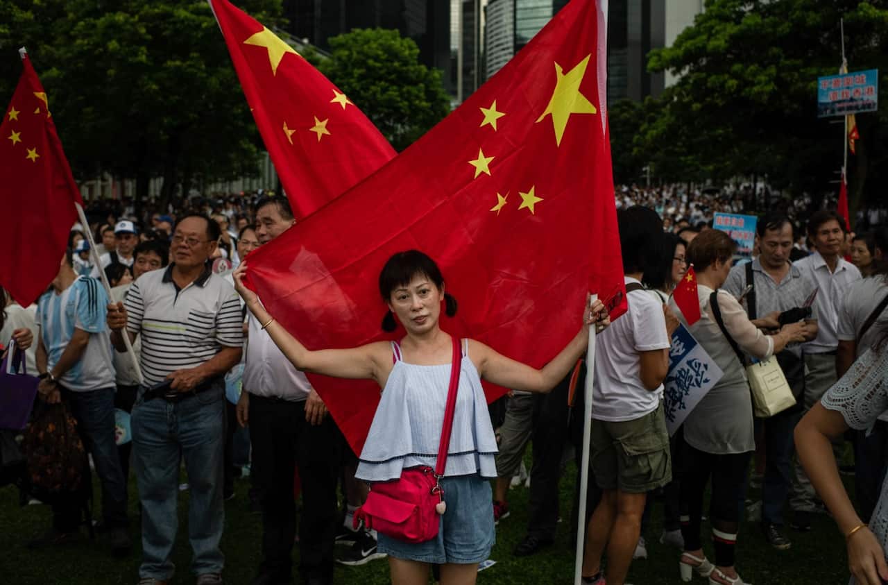 A woman embraces a Chinese flag during pro-government Safeguard Hong Kong rally at Tamar Park