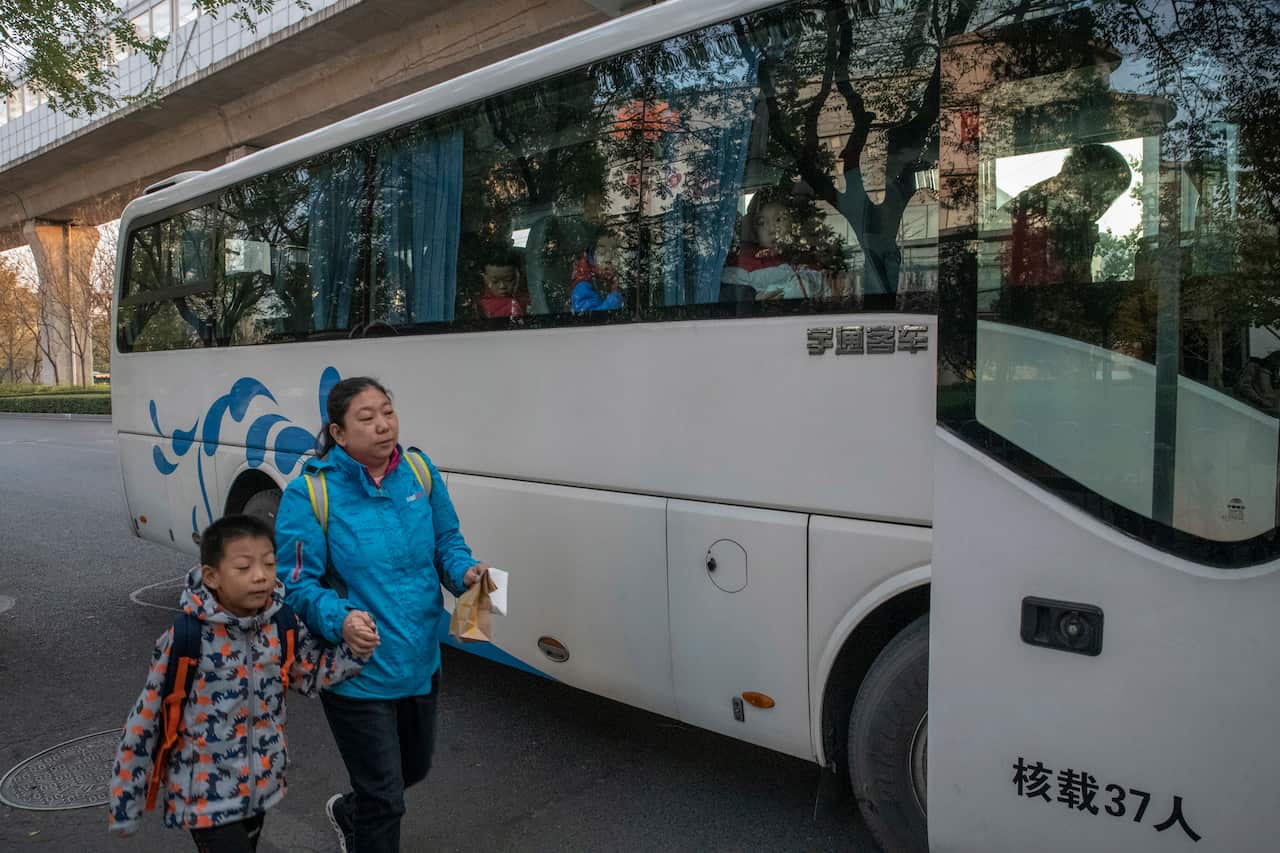 A mother brings her son to the Real Boys Club bus that will take enrolled boys to the sports school in Beijing.