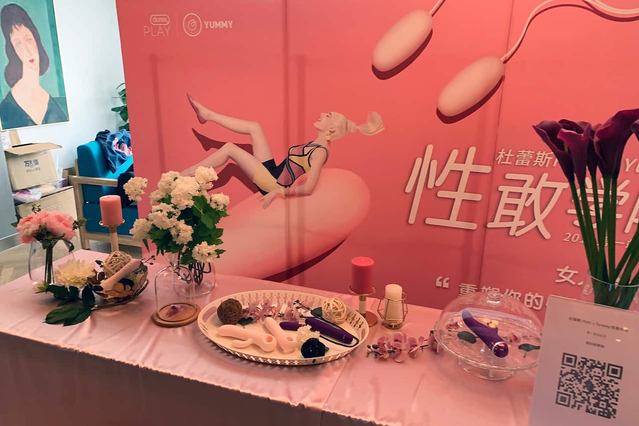 Sex toys are displayed at one of Yummy's workshops in Beijing, with a billboard that says Here, you will complete your sexual transformation!