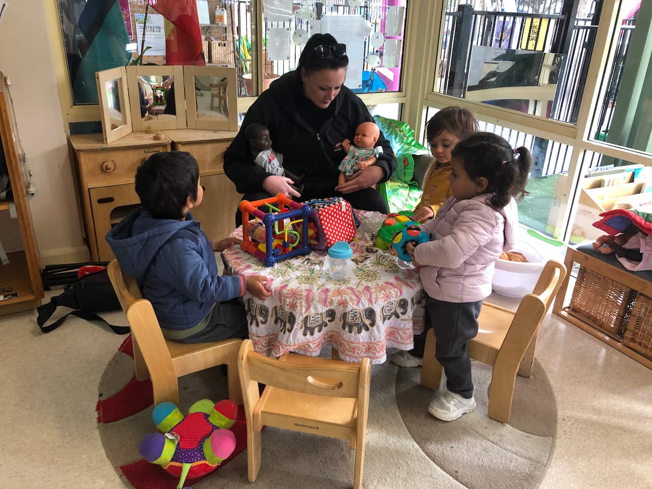 One of the Uniting's educators plays dolls with three children