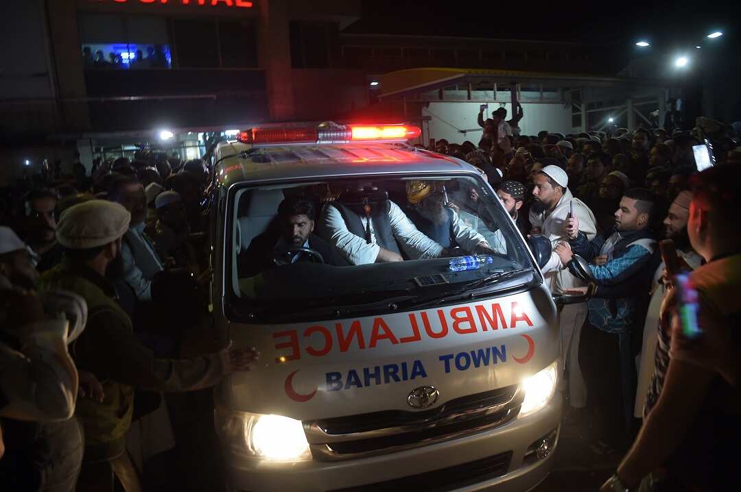 Pakistani supporters gather around an ambulance carrying the body of a key cleric Maulana Sami ul-Haq.