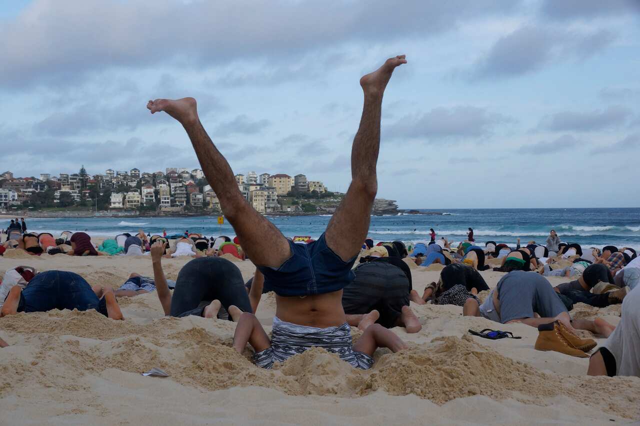 Protesters bury their heads in the sand to rally for climate change action. (AAP Image/350.org Australia, Tim Cole)