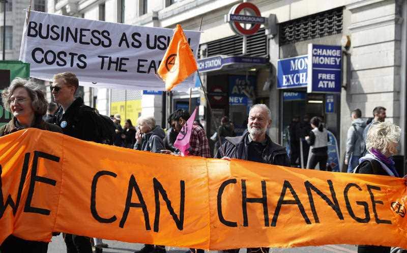 Climate change protesters hold up a banner saying 'We can Change" during a demonstration in London.