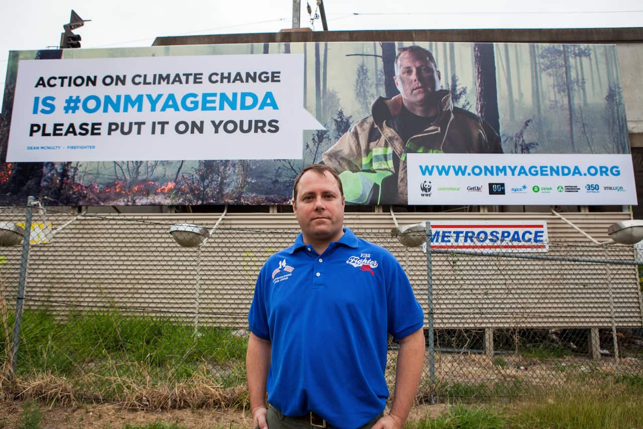 Dean McNulty poses in front of a billboard deemed "too political" for G20 Summit.