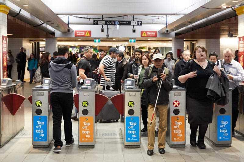 Commuters pass through barriers at a train station.