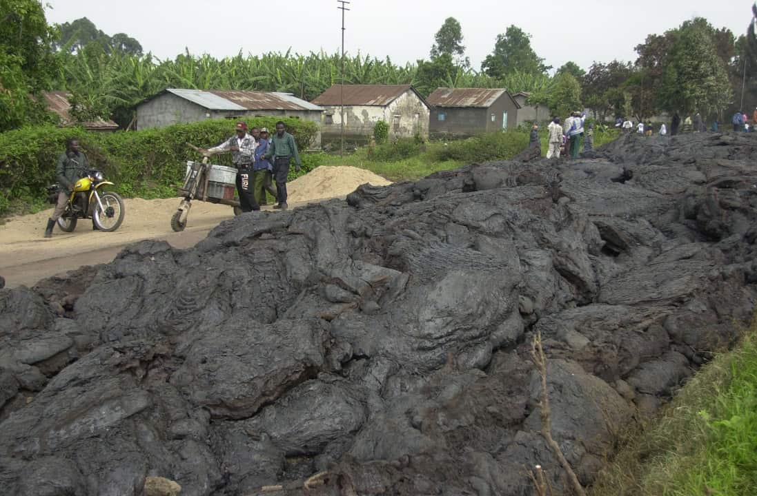 Villagers walk on the side of the road avoiding  hot lava rocks in Ndosho, on the outskirts of Goma.