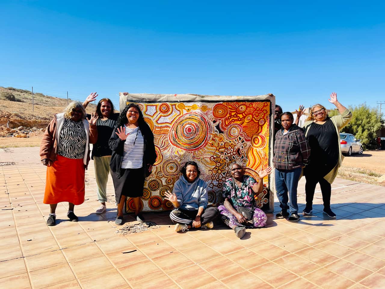 Artists from from the Umoona Art Centre collective in Coober Pedy with a painting outside.