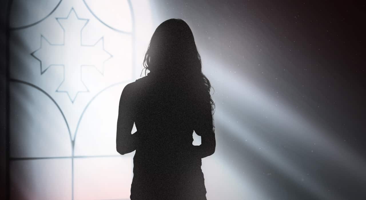 A woman stands near a church window