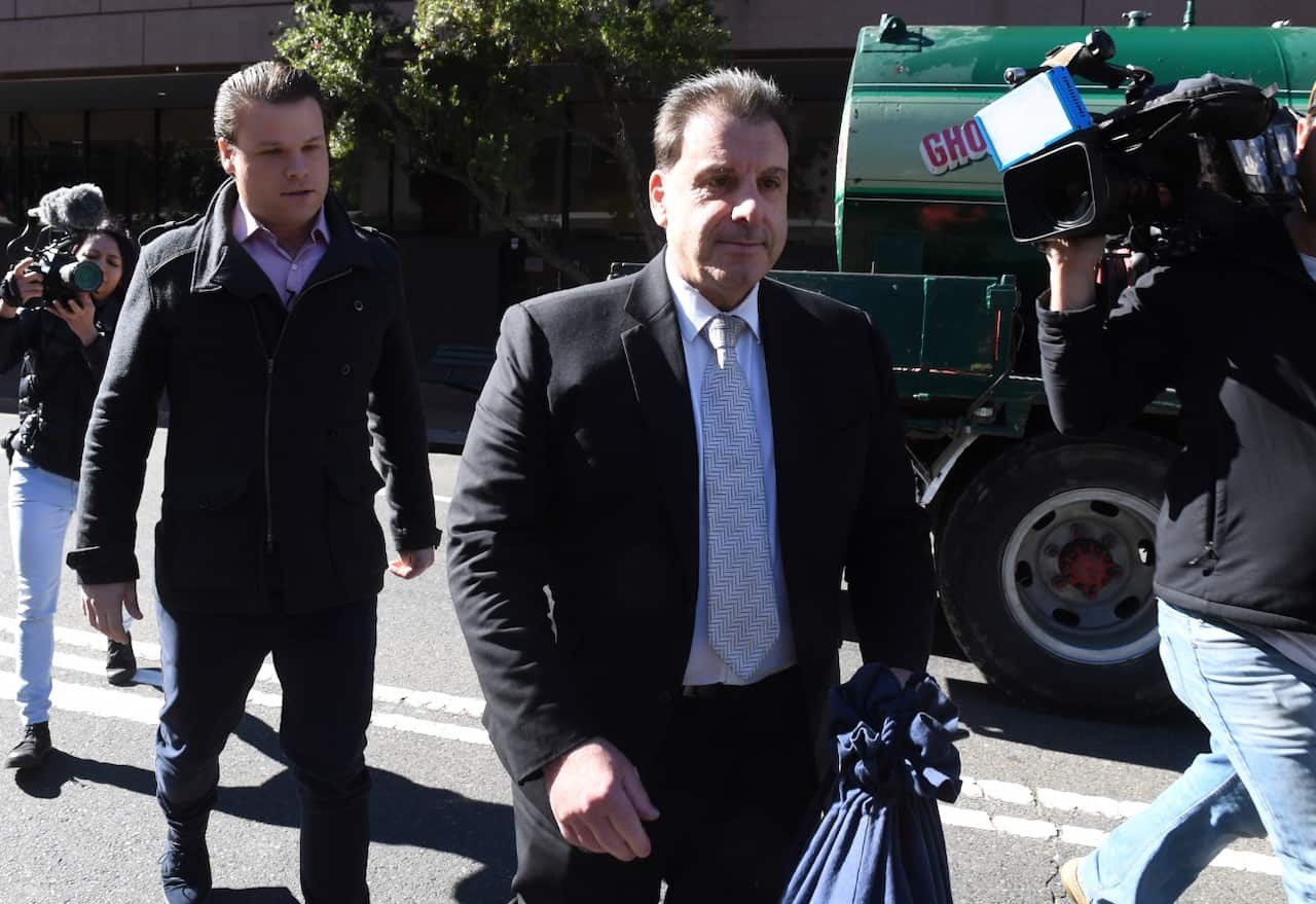 Michael Coroneos (centre), the lawyer for two terror suspects, leaves the Parramatta Local Court following a brief appearance (AAP)
