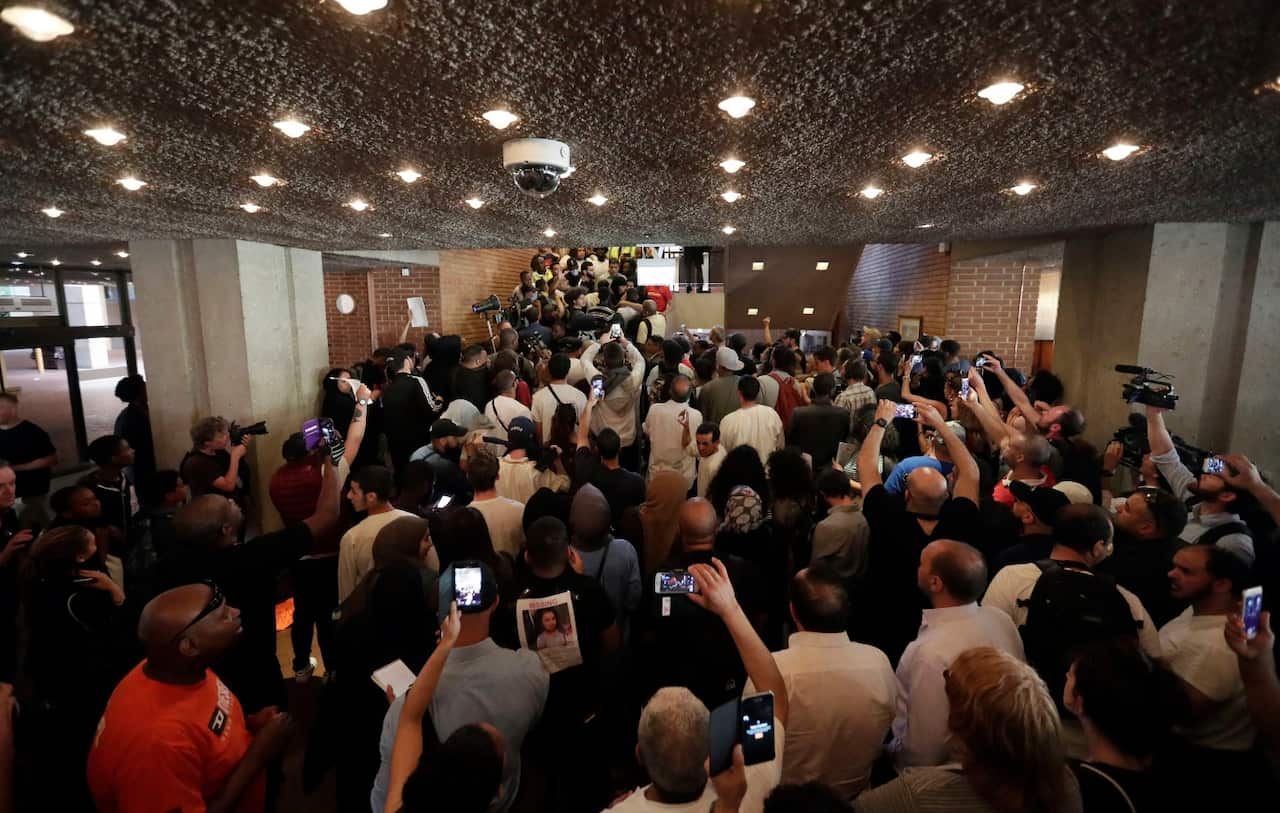 Protesters stand in the lobby of Kensington town hall in west London, the headquarters of the Royal Borough of Kensington and Chelsea (AAP)