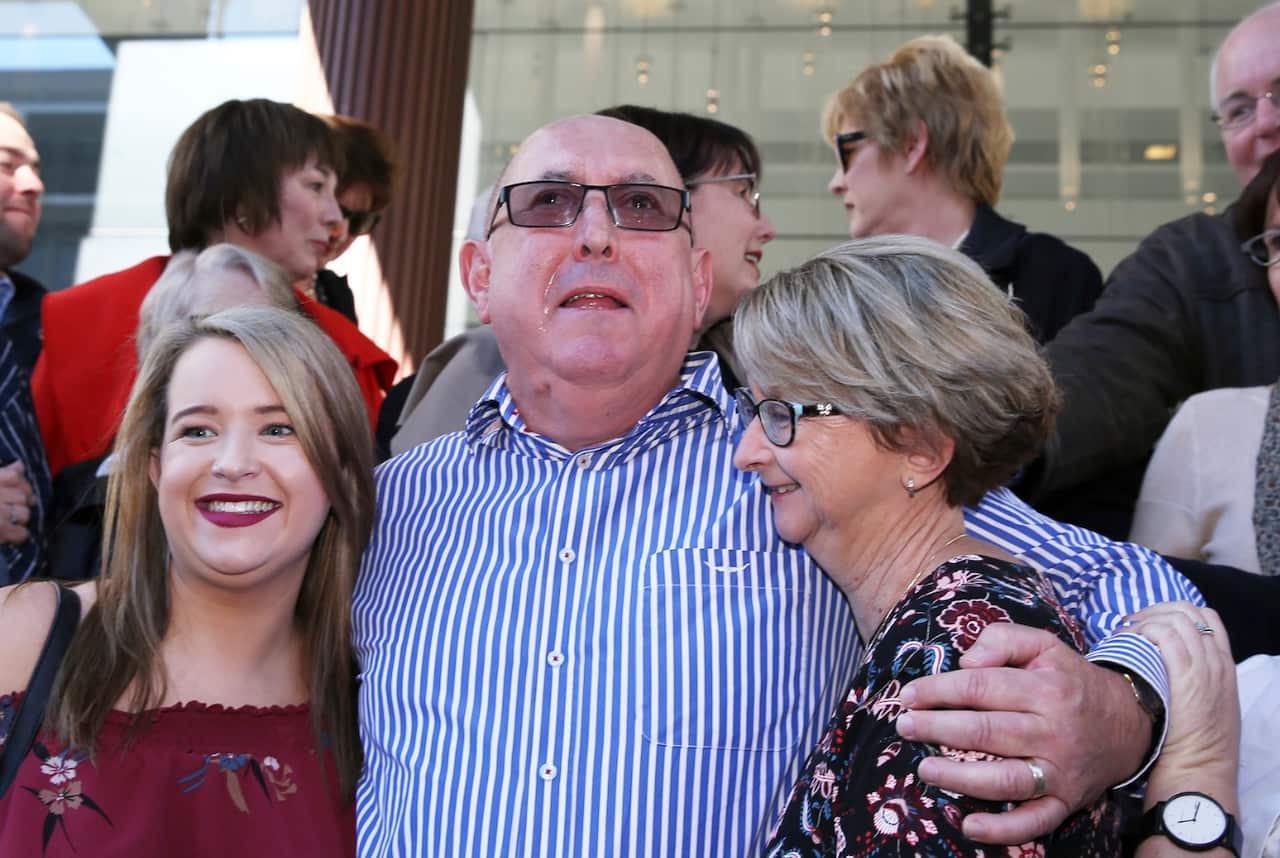 Victim Peter Creigh embraces family members outside the Newcastle Court in Newcastle, Tuesday, May 22, 2018. 