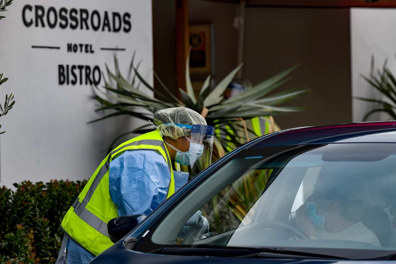 NSW Health workers dressed in Personal Protective Equipment administer COVID-19 tests to people in their cars at the Crossroads Hotel testing centre in Sydney. 