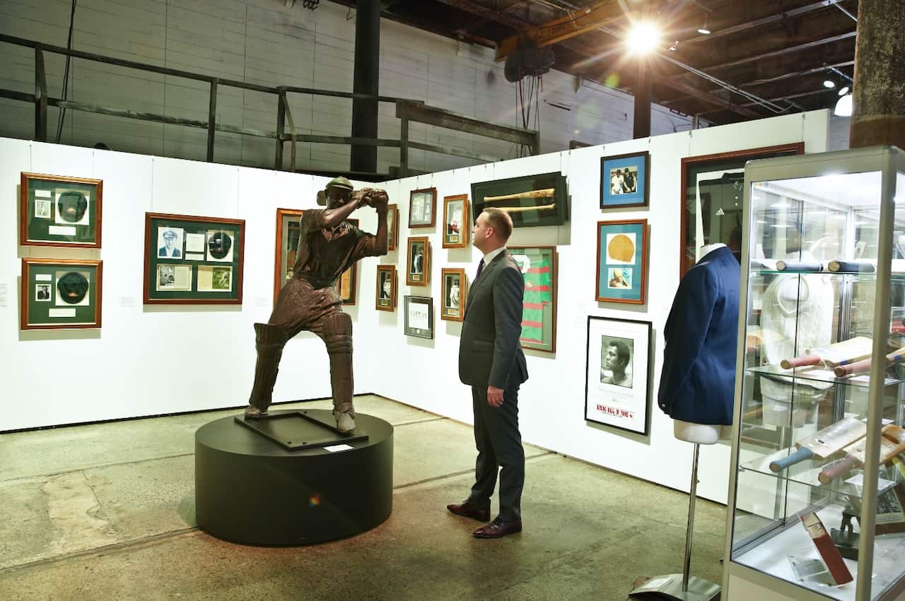 John Keats from Sotheby's Australia stands with cricket items at the auction