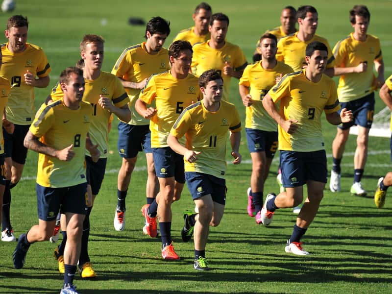 a group of football players are running on grass as they warm up