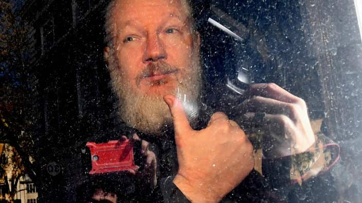 Julian Assange gestures as he arrives at Westminster Magistrates' Court following his arrest 