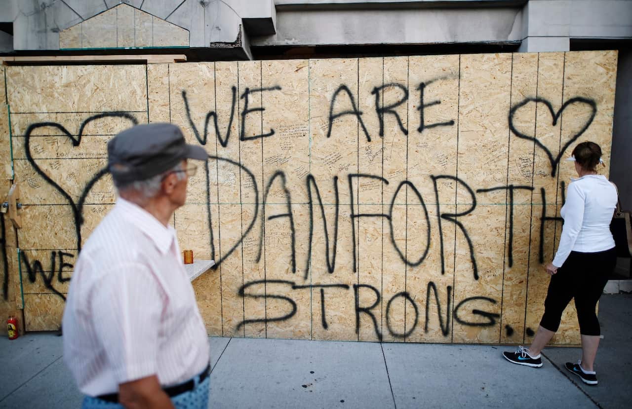 People leave personal messages on a building under renovation, remembering the victims of Sunday's shooting on and near Danforth Avenue in Toronto