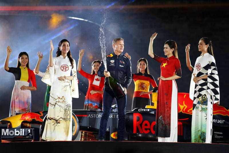 Former British Formula One driver David Coulthard (C) is flanked by Vietnamese models wearing traditional dresses during a ceremony in Hanoi, Vietnam