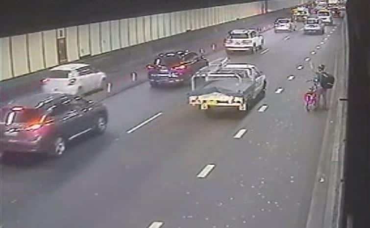 A cyclist signals to a passing ute. 