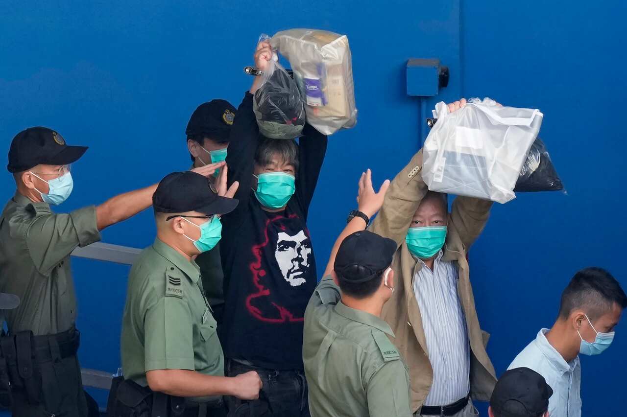 Leung Kwok-hung and Lee Cheuk-yan raise their hands as they are escorted by Correctional Services officers to a prison van on 28 May 2021.   