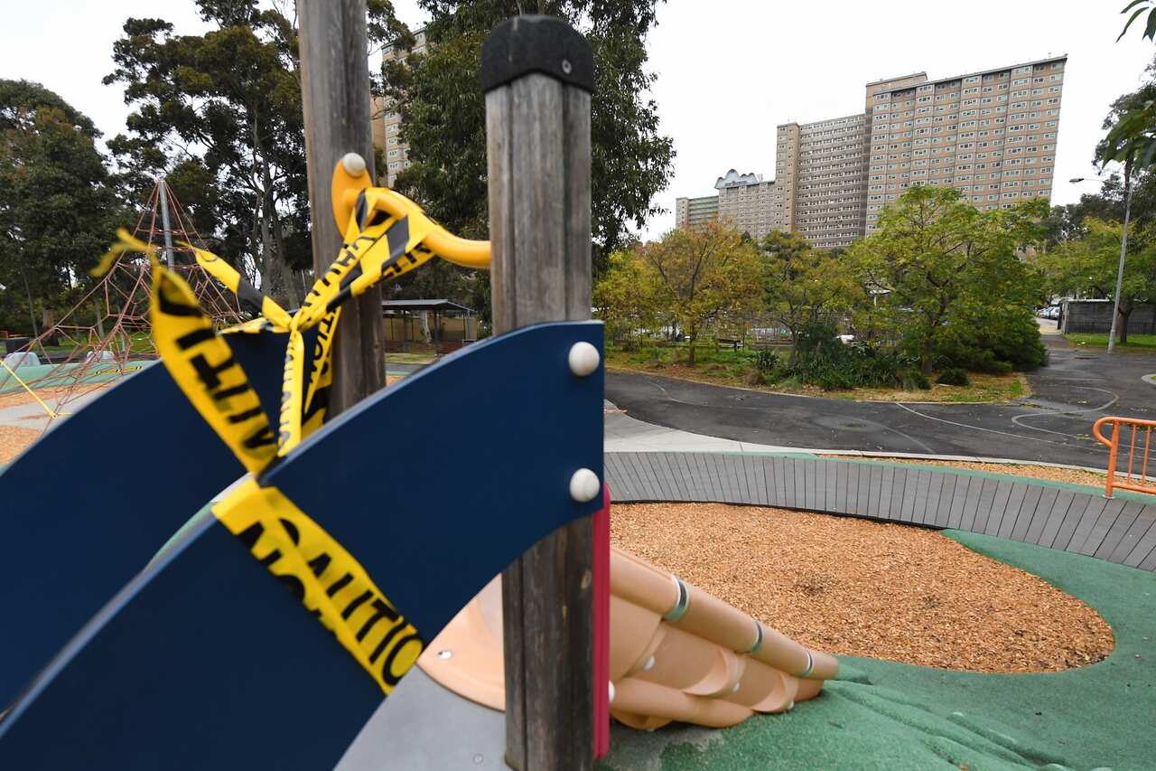 Playground equipment covered in caution tape is seen outside of a public housing tower along Racecourse Road in Melbourne.