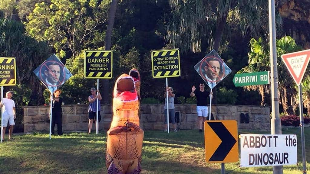 Demonstrators dress as dinosaurs greet motorists in Manly.