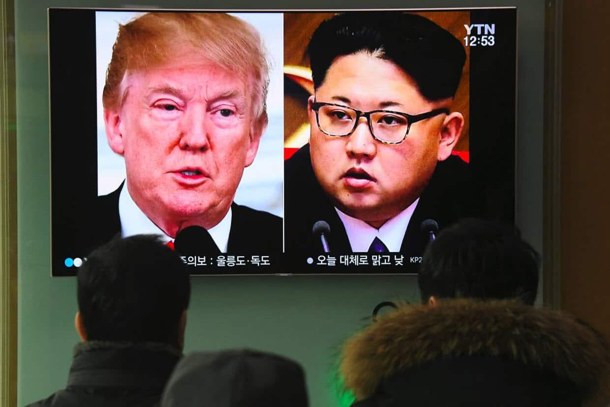 People watch a television news report showing pictures of US President Donald Trump (L) and North Korean leader Kim Jong Un at a railway station in Seoul.