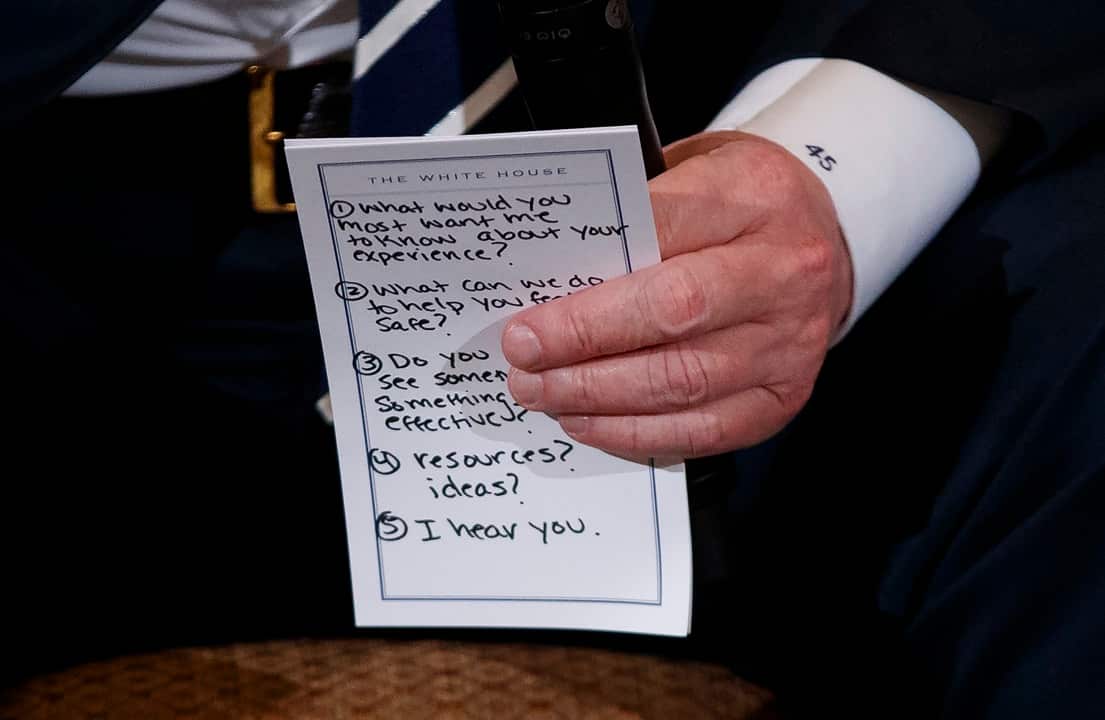 President Donald Trump holds notes during a listening session with high school students and teachers in the State Dining Room of the White House.
