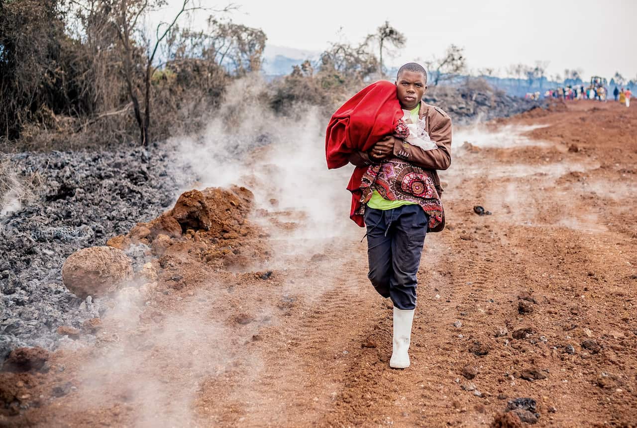 A Congolese man carries a baby as he evacuates the town of Goma in the aftermath of Mount Nyiragongo volcano over Goma.