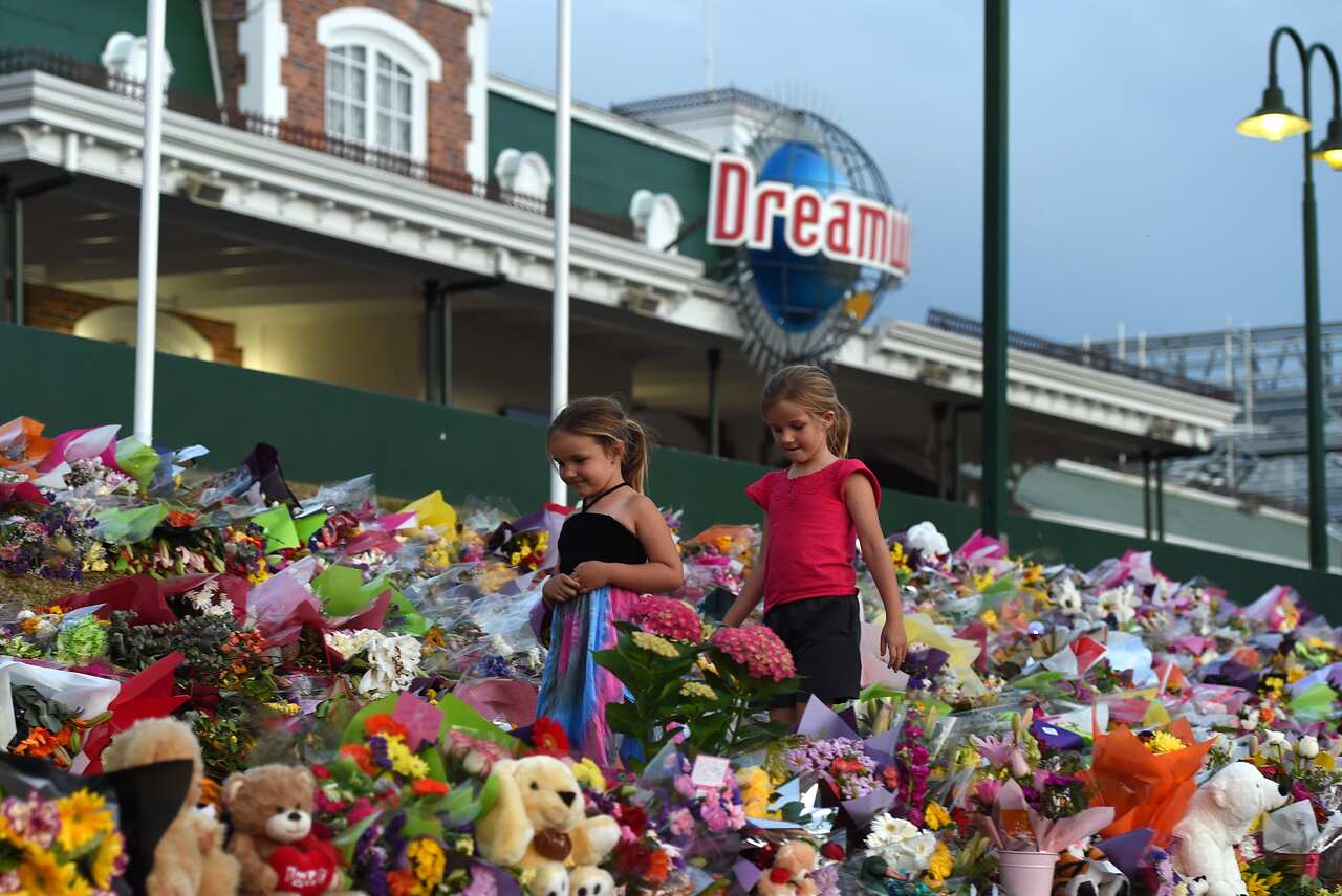 Young girls walk through a floral tribute outside Dreamworld following the October 2016 tragedy.