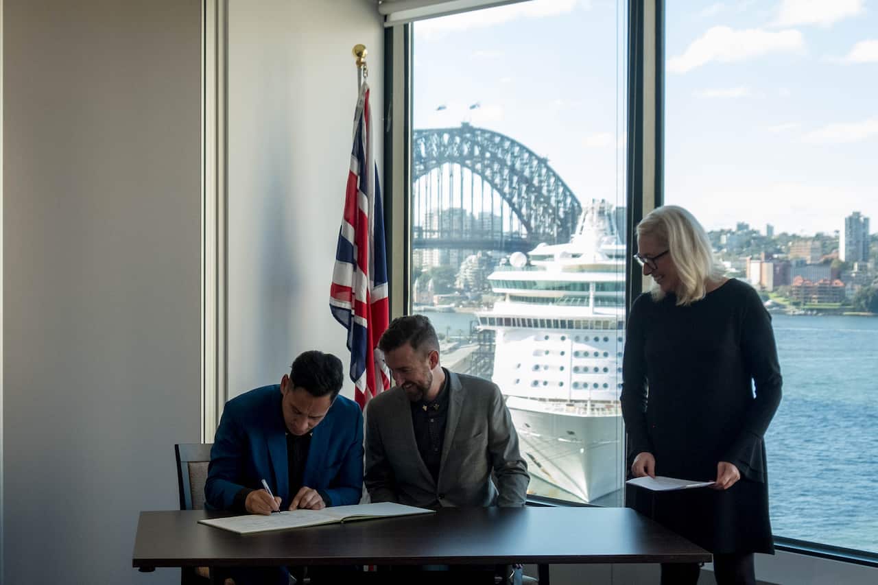 James McGill and Justin Farrell sign their marriage papers Sydney at the British consulate.
