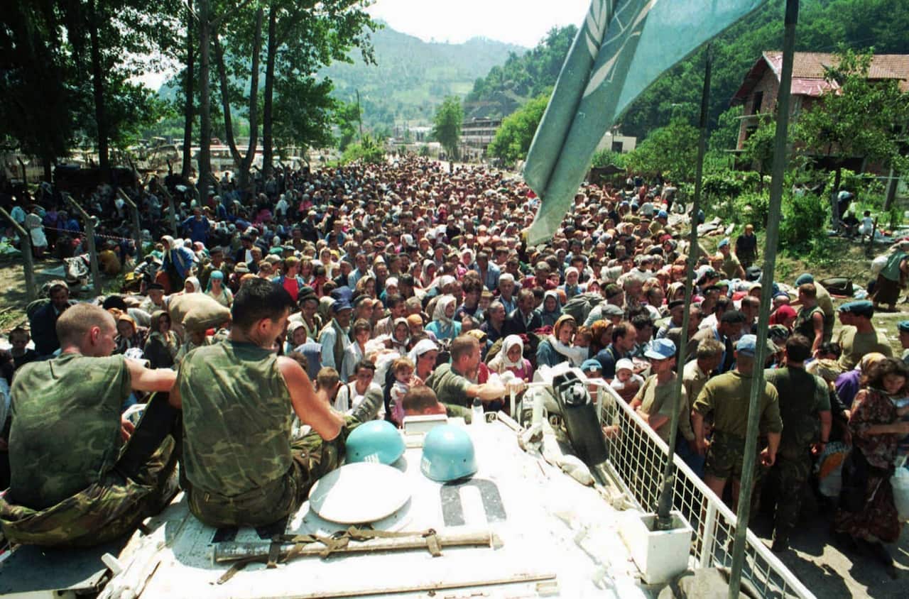 1995 file photo, Dutch U.N. peacekeepers sit on top of an armored personnel carrier while Muslim refugees from Srebrenica, eastern Bosnia, gather in the village of Potocari,
