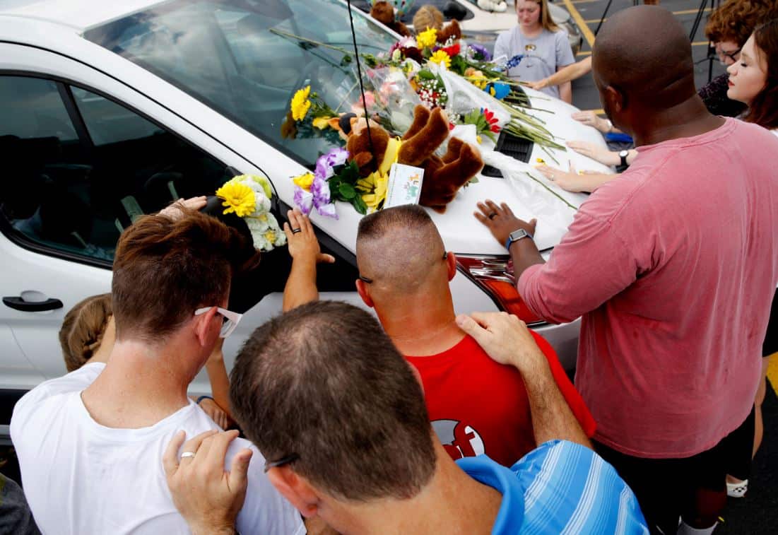 People pray around a van believed to belong to victims of a duck boat accident