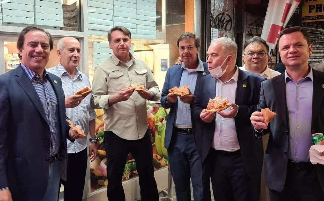 Brazil President Jair Bolsonaro (third from left) eating pizza on the sidewalk in New York City.