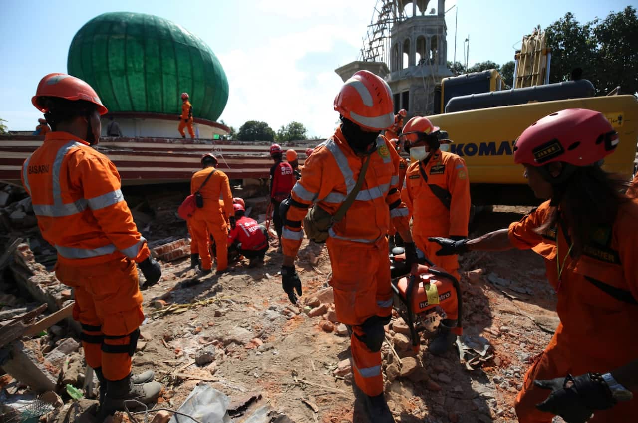 Rescue workers conduct a search around the mosque that many people were pressed under the building in Lombok Island, Indonesia on Aug. 10, 2018.
