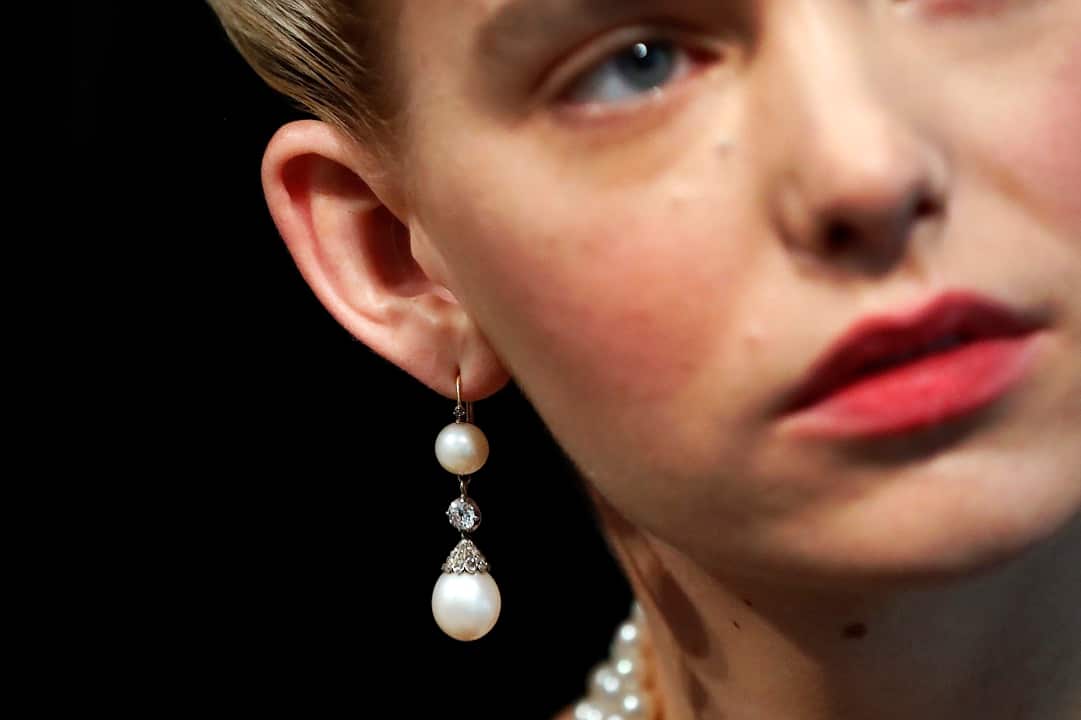 A model wears Queen Marie Antoinette's natural pearl and diamond pendant earring at Sotheby's in London.