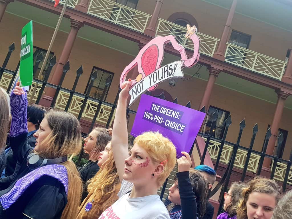 Pro-choice advocates wanting to decriminalise abortion, surround Parliament House with signs saying "It's time", "our bodies, our rights".
