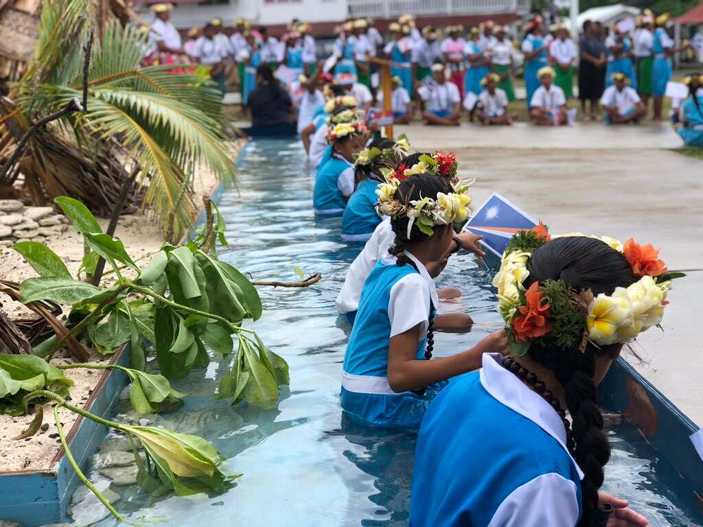 Children sitting submerged in the sea around their island home in a symbolic welcome to Pacific Leaders arriving at the Pacific Islands Forum 2019.