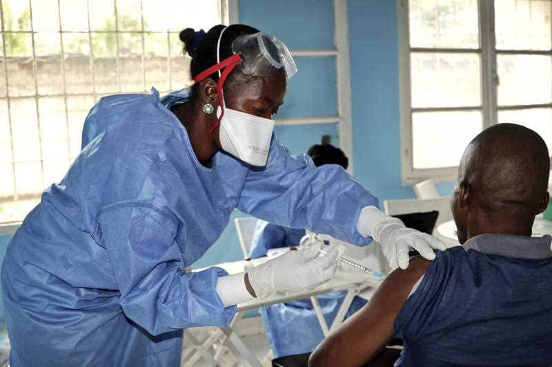 A WHO worker gives an Ebola vaccination to a front line aid worker who will then go to vaccinate locals.
