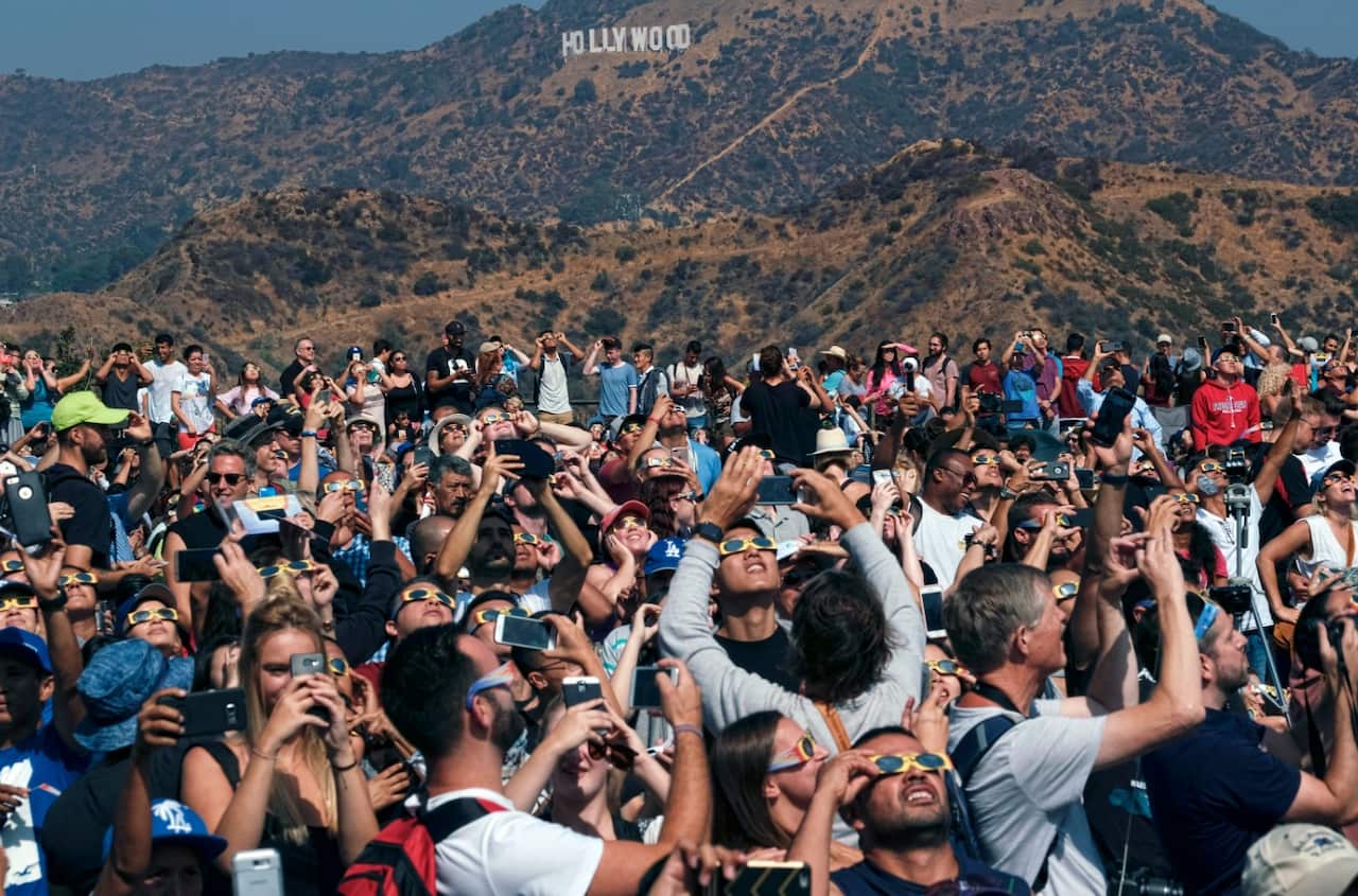 A large crowd gathers in front of the Hollywood sign at the Griffith Observatory to watch the solar eclipse in Los Angeles Monday, Aug. 21, 201 (AAP)