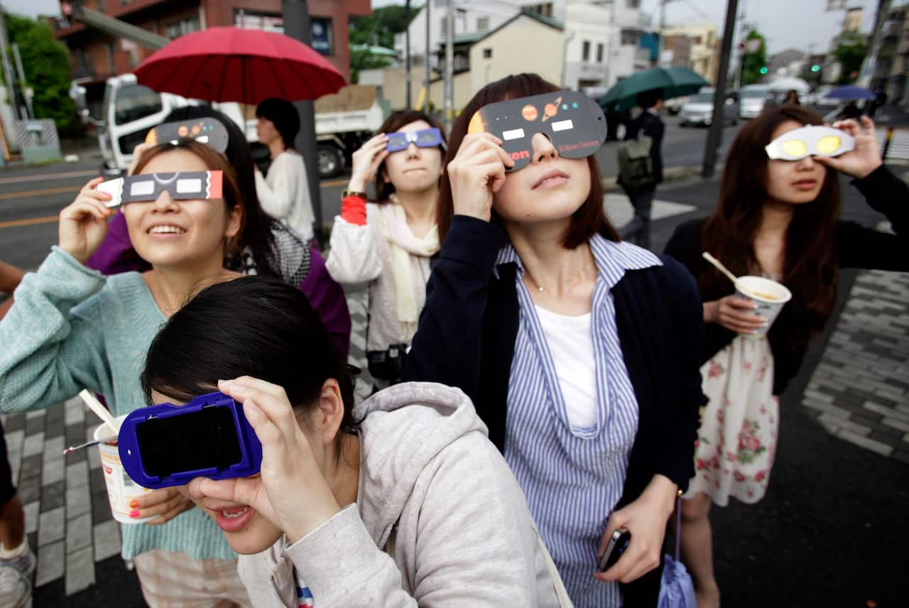 People watch the annular solar eclipse in Fujisawa, near Tokyo on 21 May 2012.
