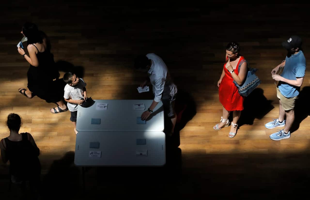 Voters pick up ballots before voting for the second round of parliamentary elections, in Lyon, central France, Sunday, June 18, 2017. (AAP)